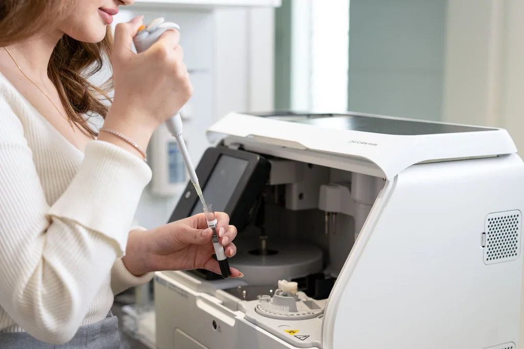 Pipettieren einer Blutprobe am Analysegerät im Praxislabor